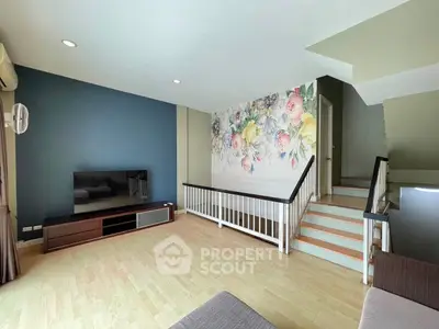 Spacious living room with floral accent wall and modern decor, perfect for relaxation and entertainment.