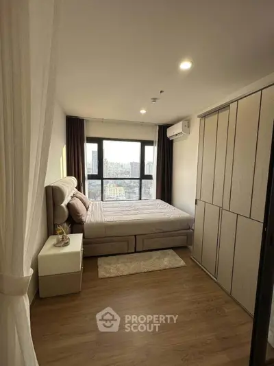 Modern bedroom with city view, featuring stylish furniture and ample natural light.