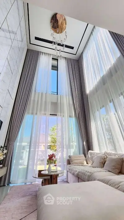 Luxurious high-ceiling living room with elegant decor and floor-to-ceiling windows