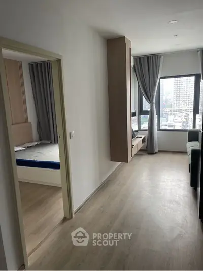 Modern apartment interior with spacious living area and bedroom, featuring large windows and stylish decor.