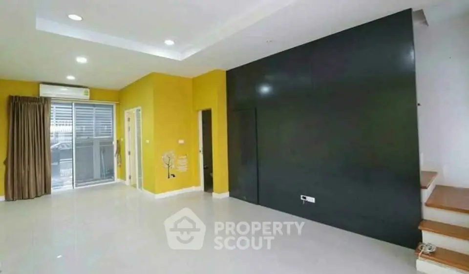 Spacious modern living room with vibrant yellow walls and sleek staircase