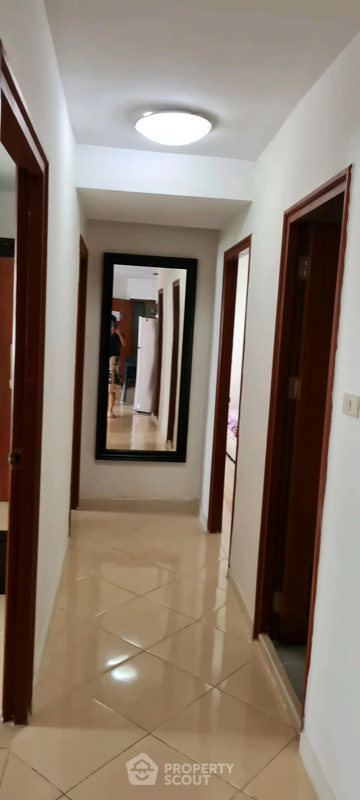 Spacious hallway with elegant tile flooring and large mirror reflecting interior design.