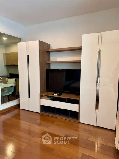 Modern living room with sleek wooden flooring and stylish entertainment unit.