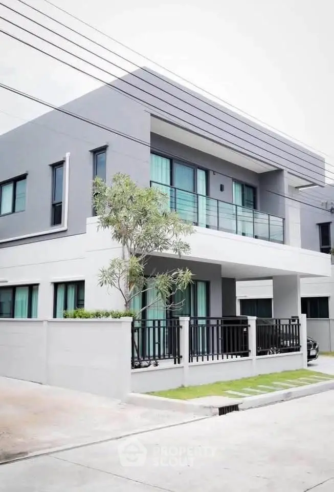 Modern two-story house with sleek design and spacious balcony in a suburban neighborhood.