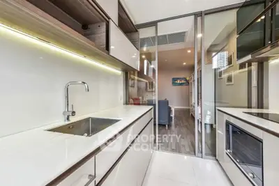 Modern kitchen with sleek cabinetry and open layout leading to living area
