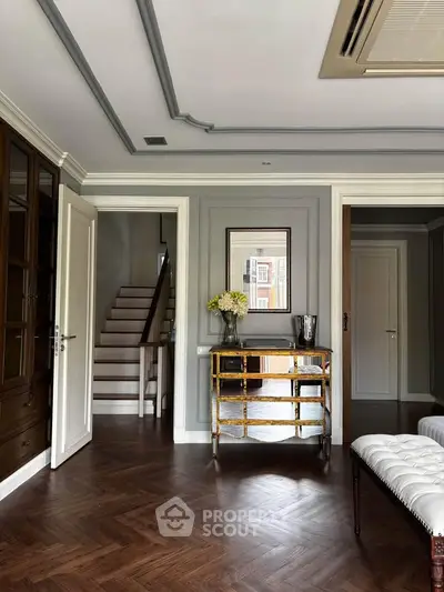 Elegant living room with parquet flooring, stylish furniture, and a staircase leading to upper level.