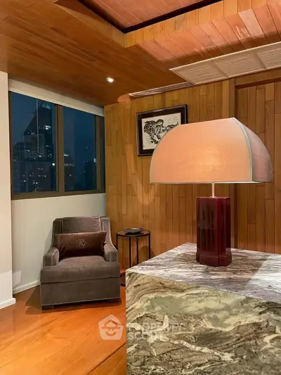 Luxurious living room with elegant decor and city view, featuring a stylish armchair and designer lamp.