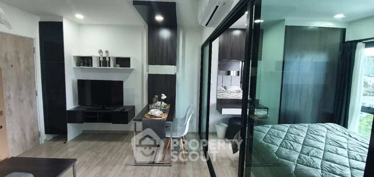 Modern studio apartment with sleek interior design and glass partitioned bedroom.