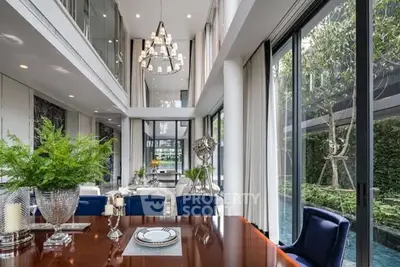 Luxurious modern dining area with high ceilings and garden view, featuring elegant decor and large windows.