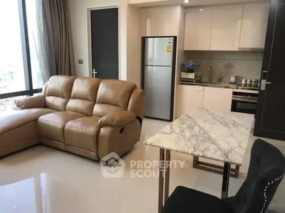 Modern living room with leather sofa and sleek kitchen in open layout apartment.