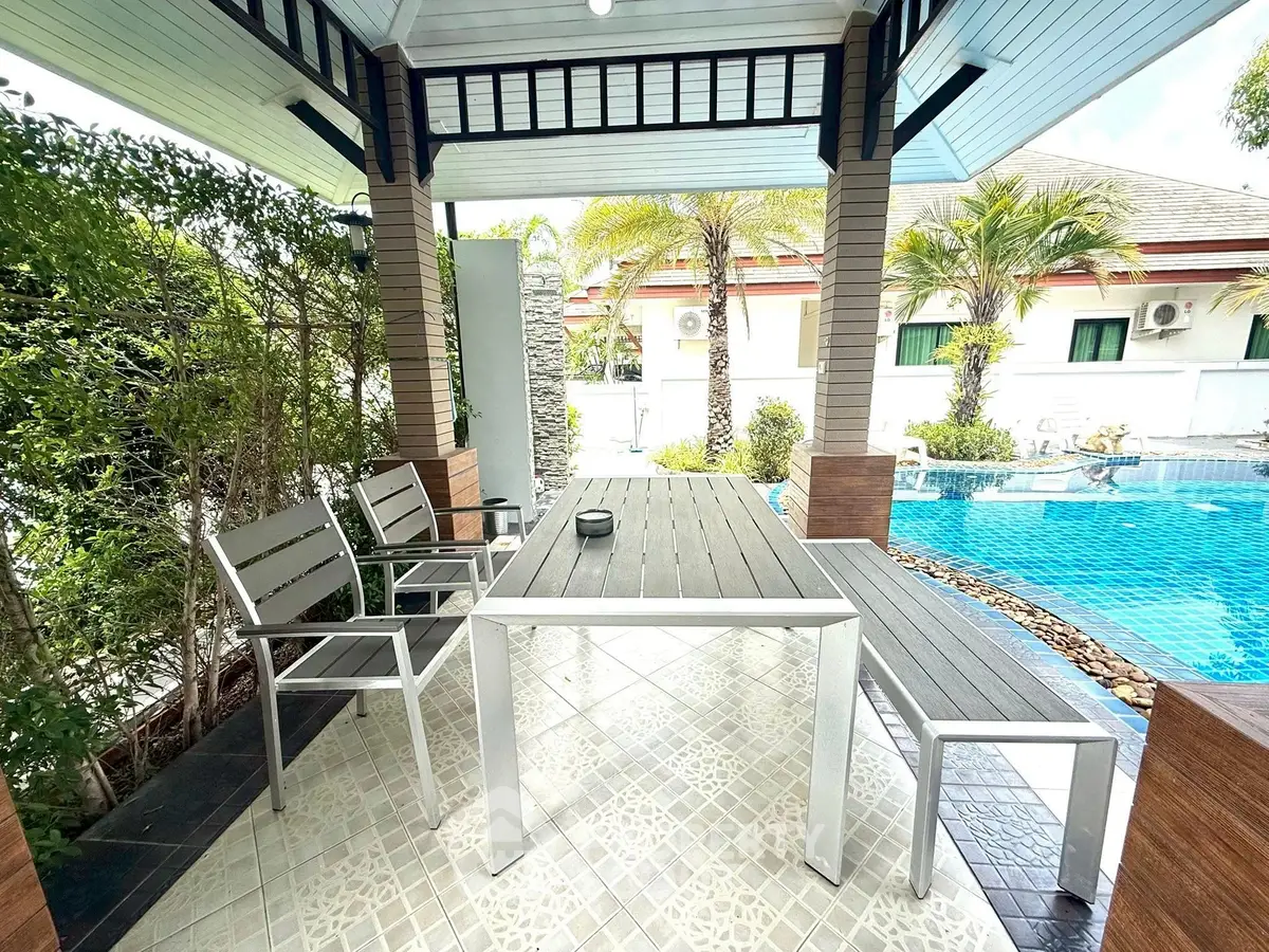 Charming outdoor patio with pool view and modern seating area, perfect for relaxation and entertaining.
