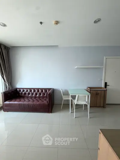 Modern living room with leather sofa and dining area in a minimalist apartment.