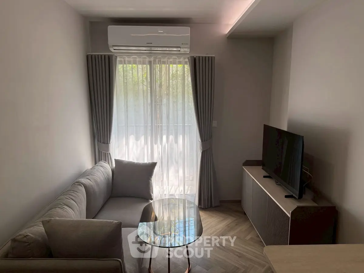 Cozy living room with modern sofa, TV, and air conditioning, perfect for relaxation.