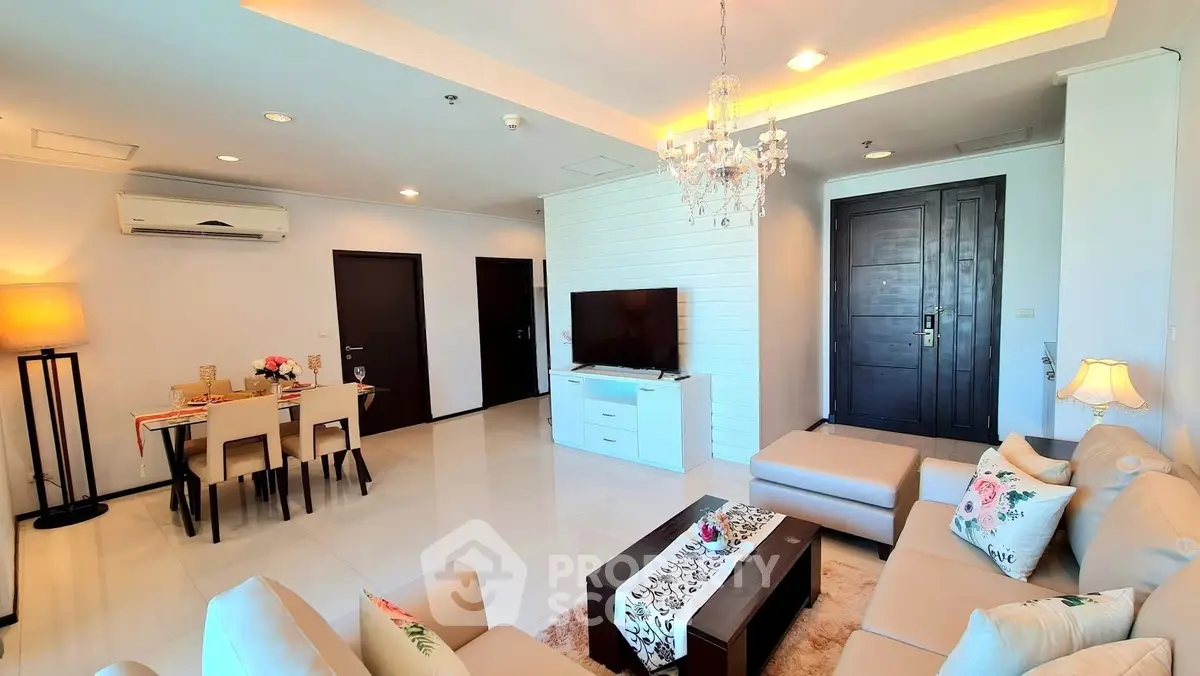 Spacious modern living room with elegant decor and dining area, featuring a chandelier and cozy seating.