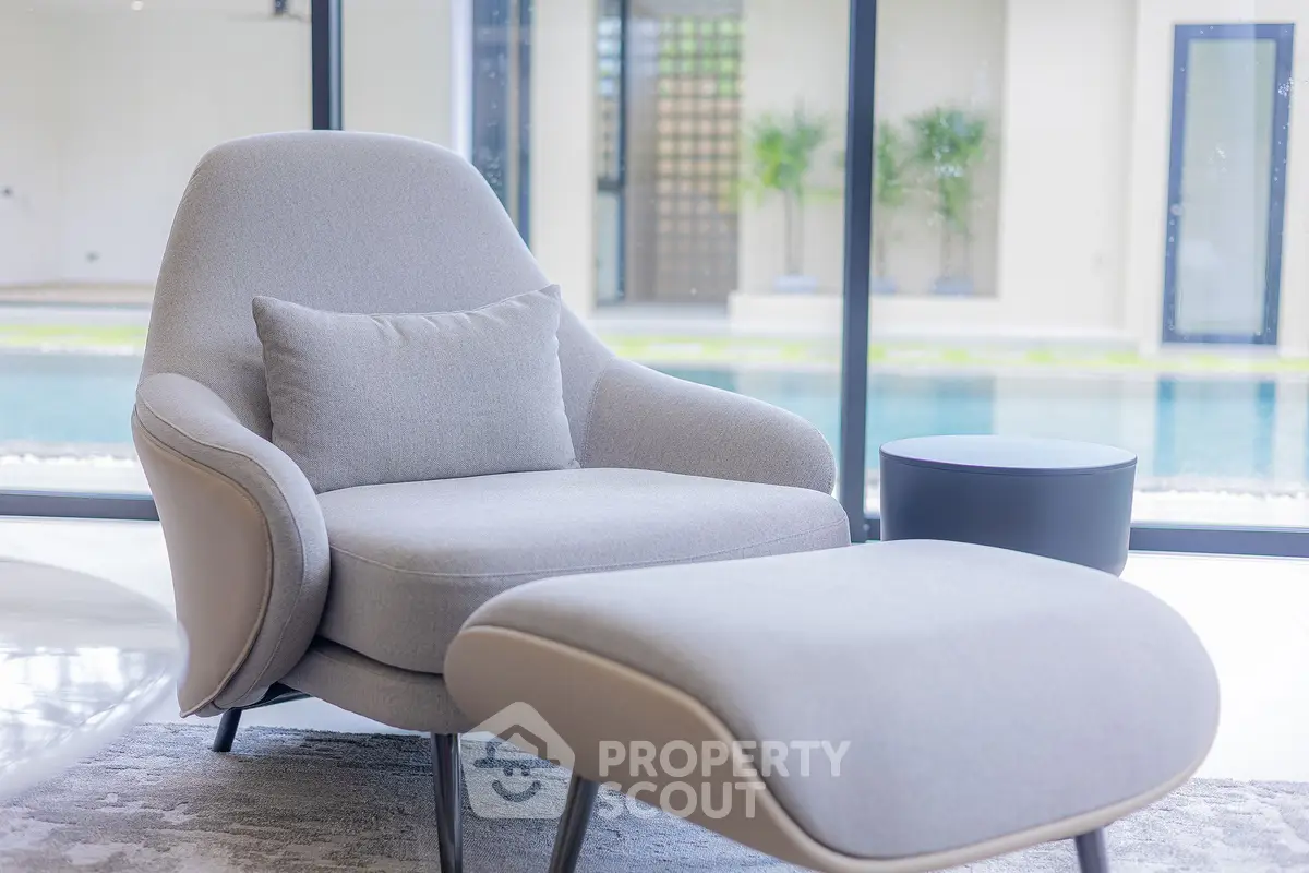 Luxurious modern living room with elegant armchair and pool view, perfect for relaxation and comfort.