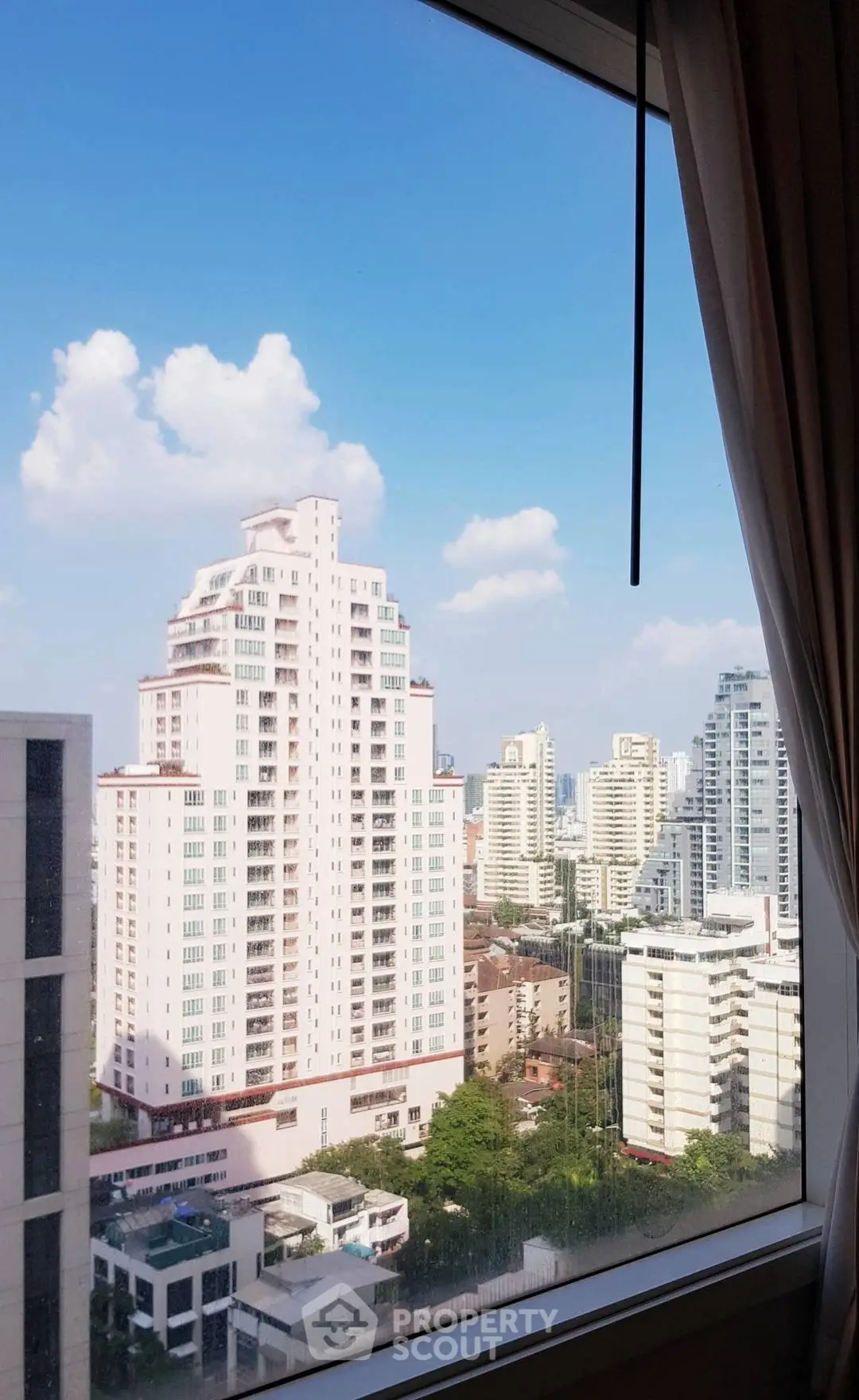Stunning cityscape view from a high-rise apartment window, showcasing modern urban living.