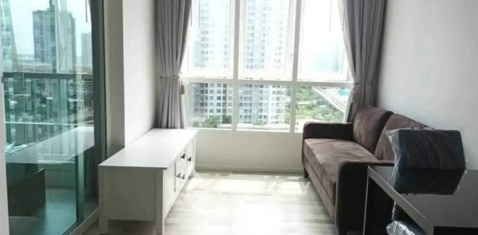 Modern living room with large windows and city view, featuring a cozy sofa and sleek furniture.