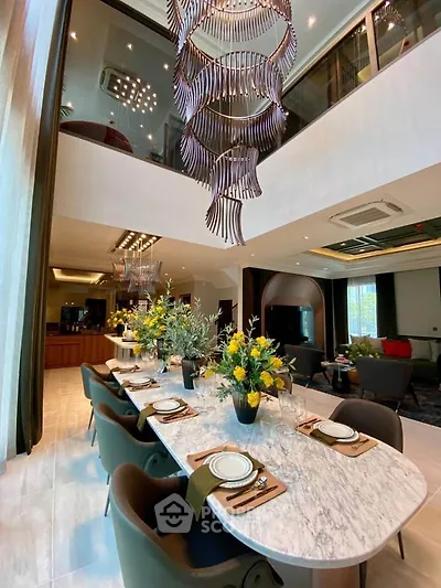 Luxurious dining area with elegant chandelier and modern decor in a spacious open-plan living room.