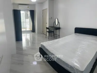 Spacious modern bedroom with balcony access and sleek furnishings in a high-rise apartment.