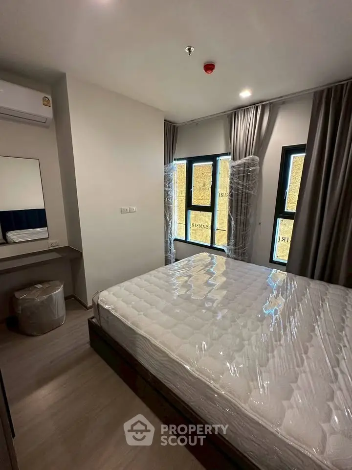 Modern bedroom with large windows and sleek furnishings in a stylish apartment.