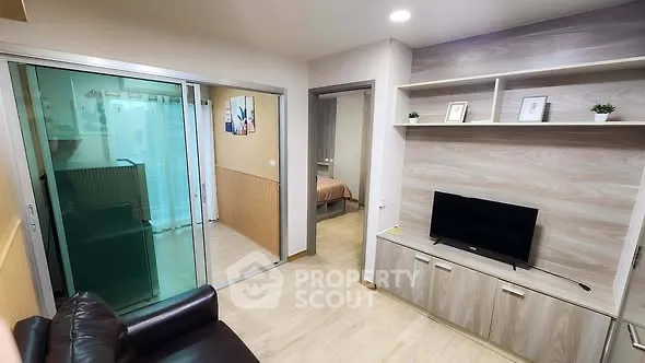 Modern living room with sleek TV unit and sliding glass doors leading to a cozy bedroom.
