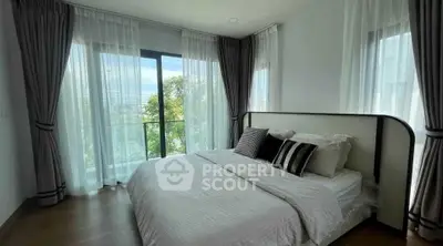 Spacious bedroom with large windows and elegant curtains, offering a serene view.