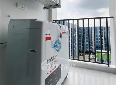 Modern balcony with washing machine and city view in high-rise apartment.