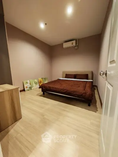 Cozy bedroom with modern decor and wooden flooring, featuring a comfortable bed and ambient lighting.