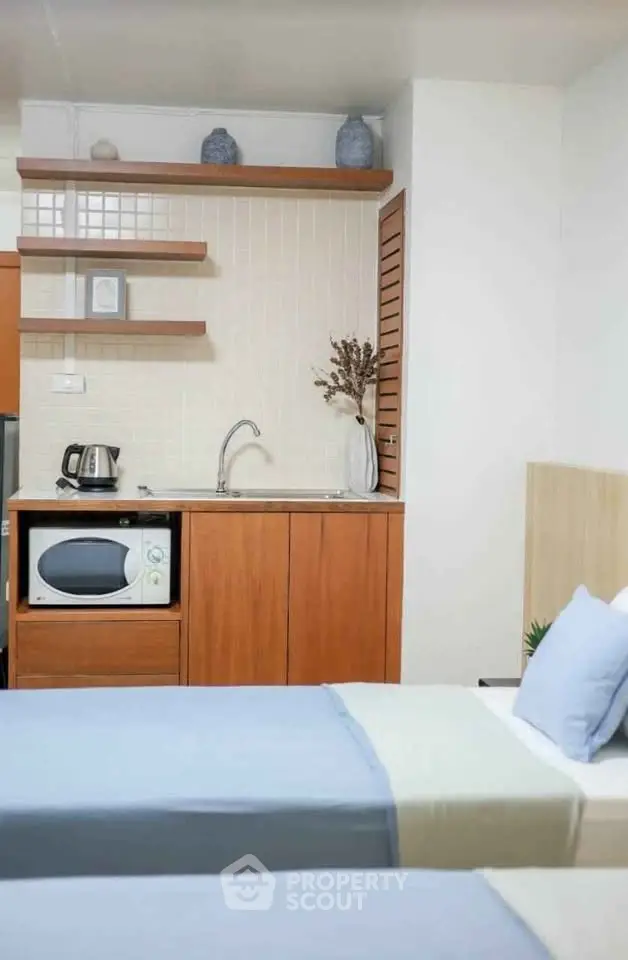 Cozy bedroom with kitchenette featuring microwave and kettle, ideal for compact living.
