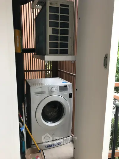 Compact laundry area with Samsung washing machine and air conditioning unit on balcony.