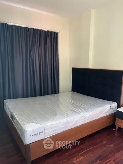 Spacious bedroom with modern bed and dark curtains, perfect for restful nights.