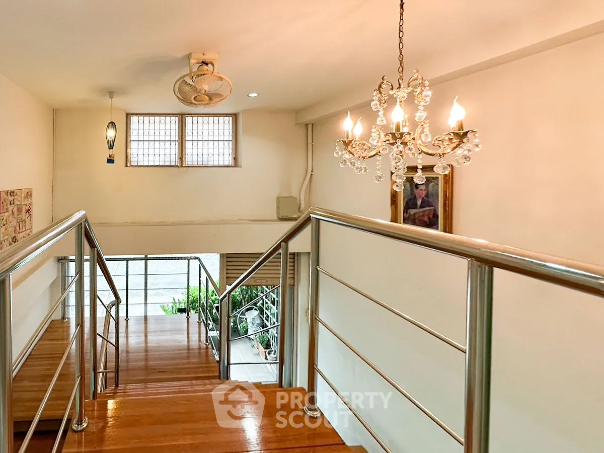 Elegant staircase with chandelier and modern railing in a stylish home interior.