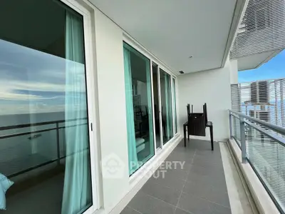 Luxurious ocean-view balcony with modern glass railing and stylish outdoor seating.
