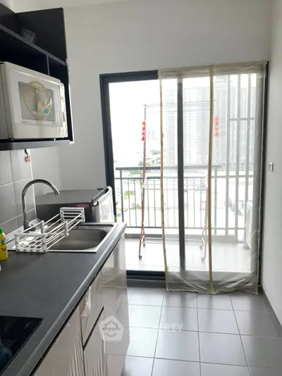 Modern kitchen with balcony view, featuring sleek countertops and appliances.