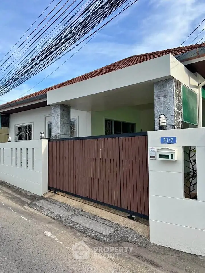 Charming single-story house with modern gate and tiled roof in a quiet neighborhood.