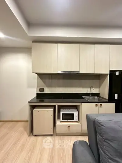Modern kitchen with sleek cabinetry and built-in microwave in a compact apartment.