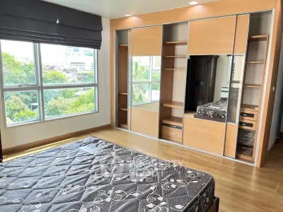 Spacious bedroom with large windows and built-in wardrobe offering natural light and storage.