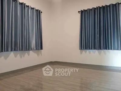 Spacious empty room with sleek tiled flooring and elegant blue curtains.