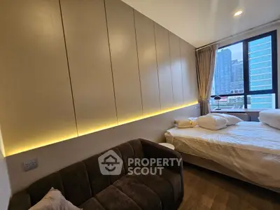 Modern bedroom with city view, featuring sleek cabinetry and cozy seating area.