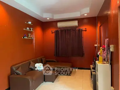 Cozy living room with brown sectional sofa and vibrant orange walls, perfect for relaxation.