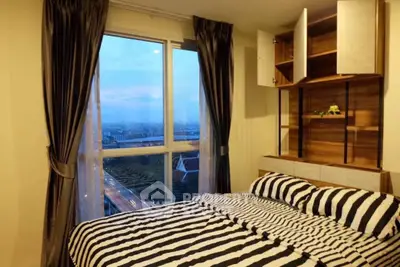 Cozy bedroom with large window offering stunning city view and stylish striped bedding.
