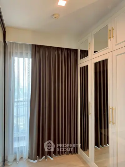 Elegant bedroom with mirrored wardrobe and floor-to-ceiling curtains, offering a stylish and functional space.
