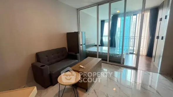 Modern studio apartment with glass partition, cozy sofa, and sleek furniture in a high-rise building.