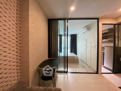 Modern apartment interior with sliding glass doors, cozy living area, and compact kitchen.