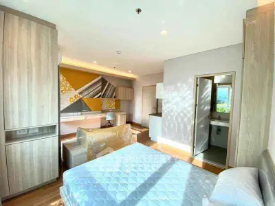 Modern bedroom with stylish decor and natural light, featuring a cozy bed and sleek furniture.