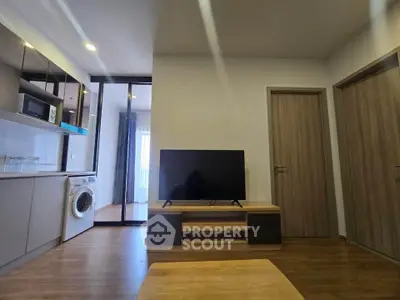 Modern living room with kitchen and laundry area, featuring sleek design and wooden flooring.