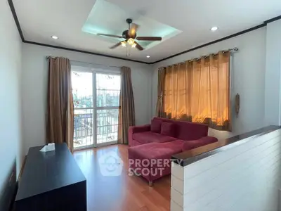 Charming living room with cozy red sofa, ceiling fan, and large windows for natural light.