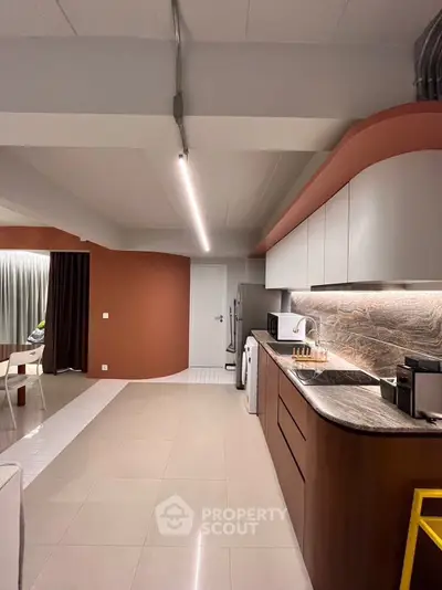 Modern kitchen with sleek design and open layout, featuring stainless steel appliances and elegant lighting.
