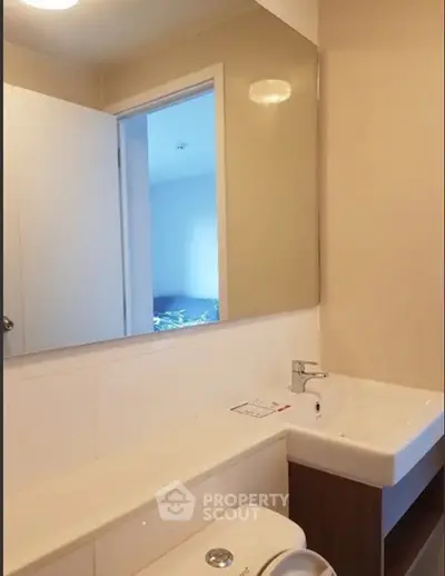Modern bathroom with sleek sink and large mirror in contemporary apartment.