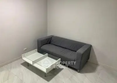Minimalist living room with gray sofa and modern glass coffee table.